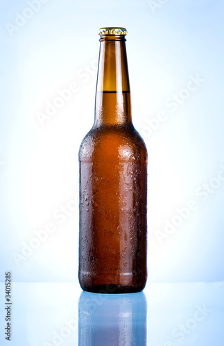 Photo: Full brown bottle with condensation on a blue background Full brown bottle with condensation on a blue background
