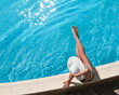 Foto: Young woman sitting on the ledge of the pool. Young woman sitting on the ledge of the pool.