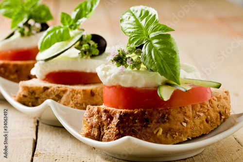 Photo: Tartine di pomodoro e mozzarella su letto di pane ai cereali Tartine di pomodoro e mozzarella su letto di pane ai cereali