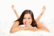 Portrait einer hübschen jungen Frau auf weißem Bett liegend Portrait einer hübschen jungen Frau auf weißem Bett liegend