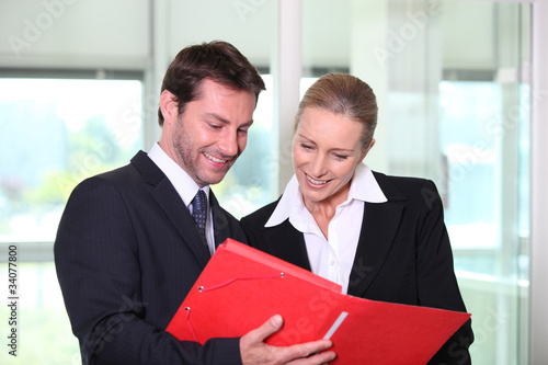Photo: Businessman and woman looking at folder Businessman and woman looking at folder