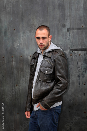 Photo: Man with leather jacket standing on metal door Man with leather jacket standing on metal door