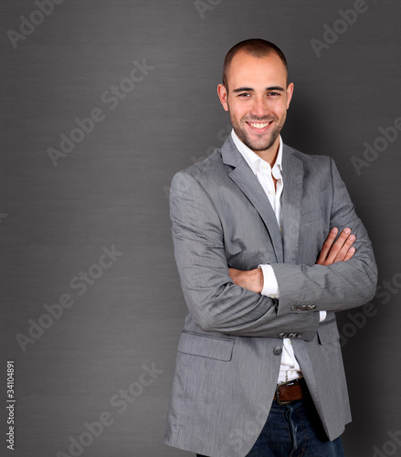 Photo: Cool businessman standing on grey background Cool businessman standing on grey background