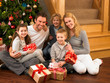 Photo: Family with gifts in front of Christmas tree Family with gifts in front of Christmas tree