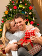 Young couple with gifts in front of Christmas tree
