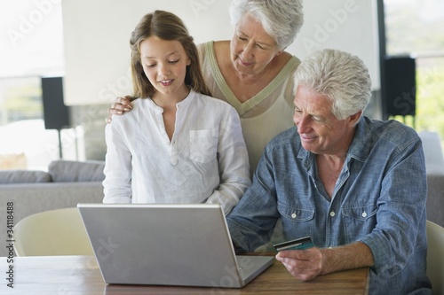Foto: Senior man doing home shopping with a credit card with his family near him Senior man doing home shopping with a credit card with his family near him