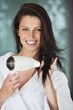 Portrait of a woman drying her hair with a hair dryer
