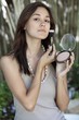 Portrait of a beautiful young woman applying make-up