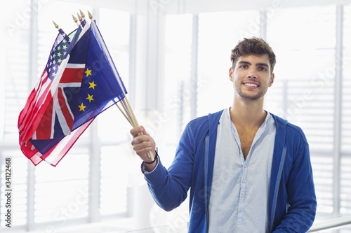 Photo: Portrait of a man holding flags of various countries at an airport Portrait of a man holding flags of various countries at an airport