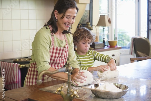 Photo: Grandmother and little boy kneading dough at kitchen Grandmother and little boy kneading dough at kitchen