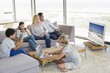 Couple watching television set while their children busy in different activities