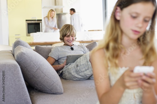 Photo: Teenage boy using a digital tablet on a couch Teenage boy using a digital tablet on a couch