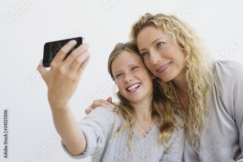 Photo: Girl with her mother taking picture of themselves with a mobile phone Girl with her mother taking picture of themselves with a mobile phone