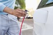 Mid section view of a mid adult man charging the electric car