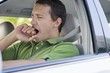 Mid adult man yawning while driving a car