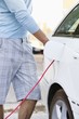Mid section view of a mid adult man charging the electric car