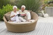 Senior couple sitting in a wicker couch reading a magazine