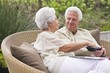 Senior couple sitting in a wicker couch eating food