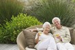 Senior couple sitting in a wicker couch holding wine glasses