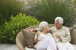 Senior couple sitting in a wicker couch and smiling