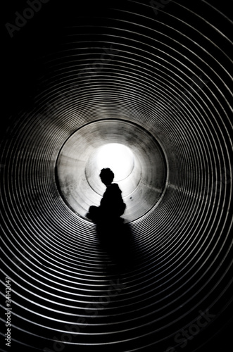 Foto: The silhouette of sitting boy with light at the end of tunnel The silhouette of sitting boy with light at the end of tunnel