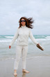 Barefooted woman on the beach against sea and cloudy sky.