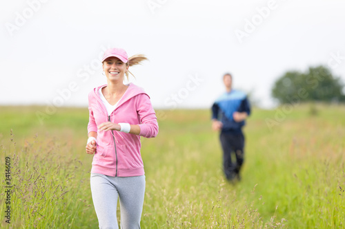 Foto: Jogging sportive young couple running meadow field Jogging sportive young couple running meadow field