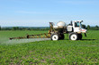 Foto: Close up side view of tractor spraying pesticides on crop Close up side view of tractor spraying pesticides on crop