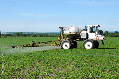 Photo: Close up side view of tractor spraying pesticides on crop Close up side view of tractor spraying pesticides on crop