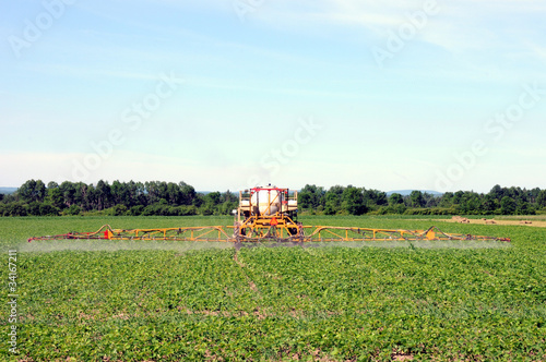 Photo: Full rear view of tractor spraying pesticides on crop Full rear view of tractor spraying pesticides on crop