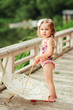 cute little girl in swimsuit with sun umbrella taking sunbathe