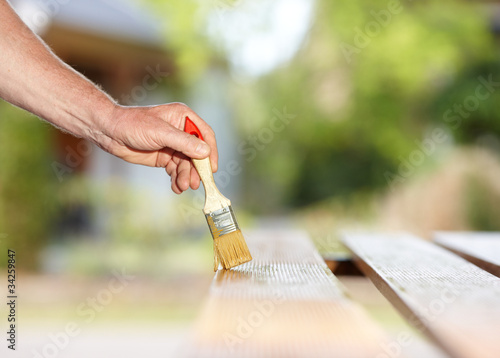Photo: Mann streicht Brett mit Pinsel Mann streicht Brett mit Pinsel
