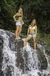 two teenage sisters standing in a waterfall in hawaii
