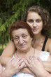 Young woman with her elderly mother against firtree