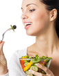 Young happy smiling woman eating vegetable salad, isolated Young happy smiling woman eating vegetable salad, isolated