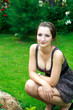 Beautiful girl sitting on green bright grass near fir tree Beautiful girl sitting on green bright grass near fir tree