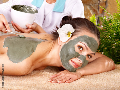 Photo: Young woman having clay body mask. Young woman having clay body mask.