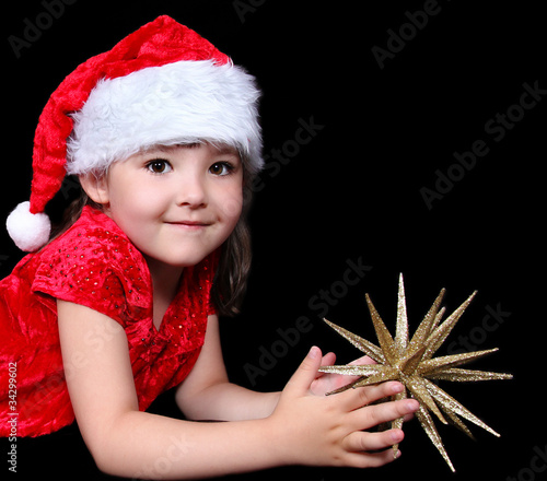Photo: close-up of sweet little girl in santa hat laying on floor with close-up of sweet little girl in santa hat laying on floor with