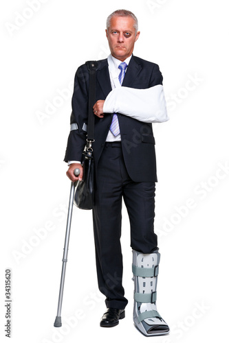 Photo: Injred businessman on crutches isolated on white Injred businessman on crutches isolated on white