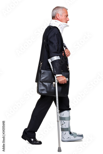 Foto: Injred businessman on crutches isolated on white Injred businessman on crutches isolated on white