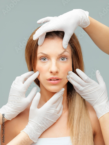 Photo: beautiful face being examinated plastic surgeons hands beautiful face being examinated plastic surgeons hands