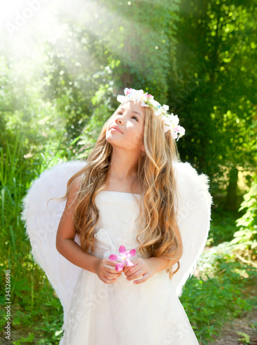 Photo: Angel children girl in forest with flower in hand Angel children girl in forest with flower in hand