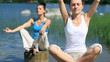 Two young women meditating by the lake