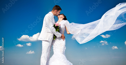 Photo: newly married couple.wind lifting long white bridal wedding newly married couple.wind lifting long white bridal wedding