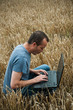 Photo: agriculteur et ordinateur dans un champ de blé agriculteur et ordinateur dans un champ de blé