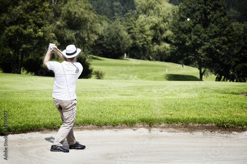 Photo: Golfer chipping in bunker. Golfer chipping in bunker.