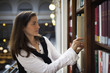 Student pulling out book from bookshelf