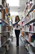 Student between bookshelves reading