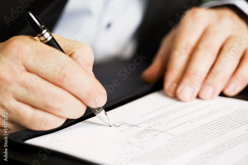 Foto: Close up of businessman signing a contract. Close up of businessman signing a contract.