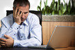 Frustrated businessman at laptop.